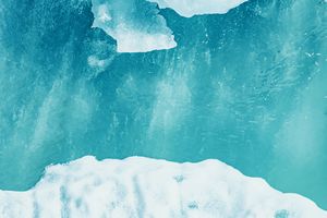 Aerial view of turquoise glacial ice and snow formations with stunning blue water patterns.