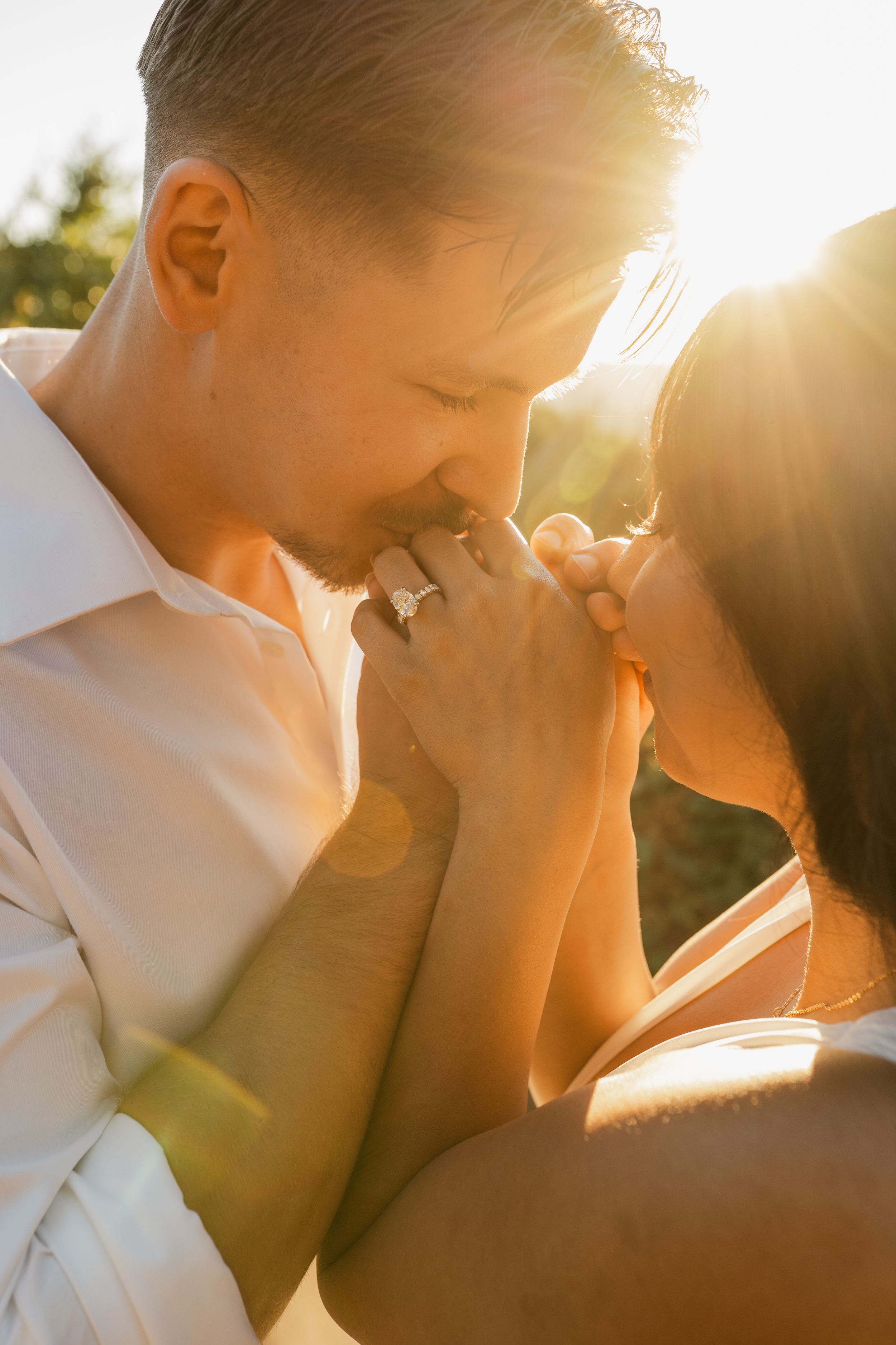 Romantic couple embracing in golden sunlight during sunset outdoors.