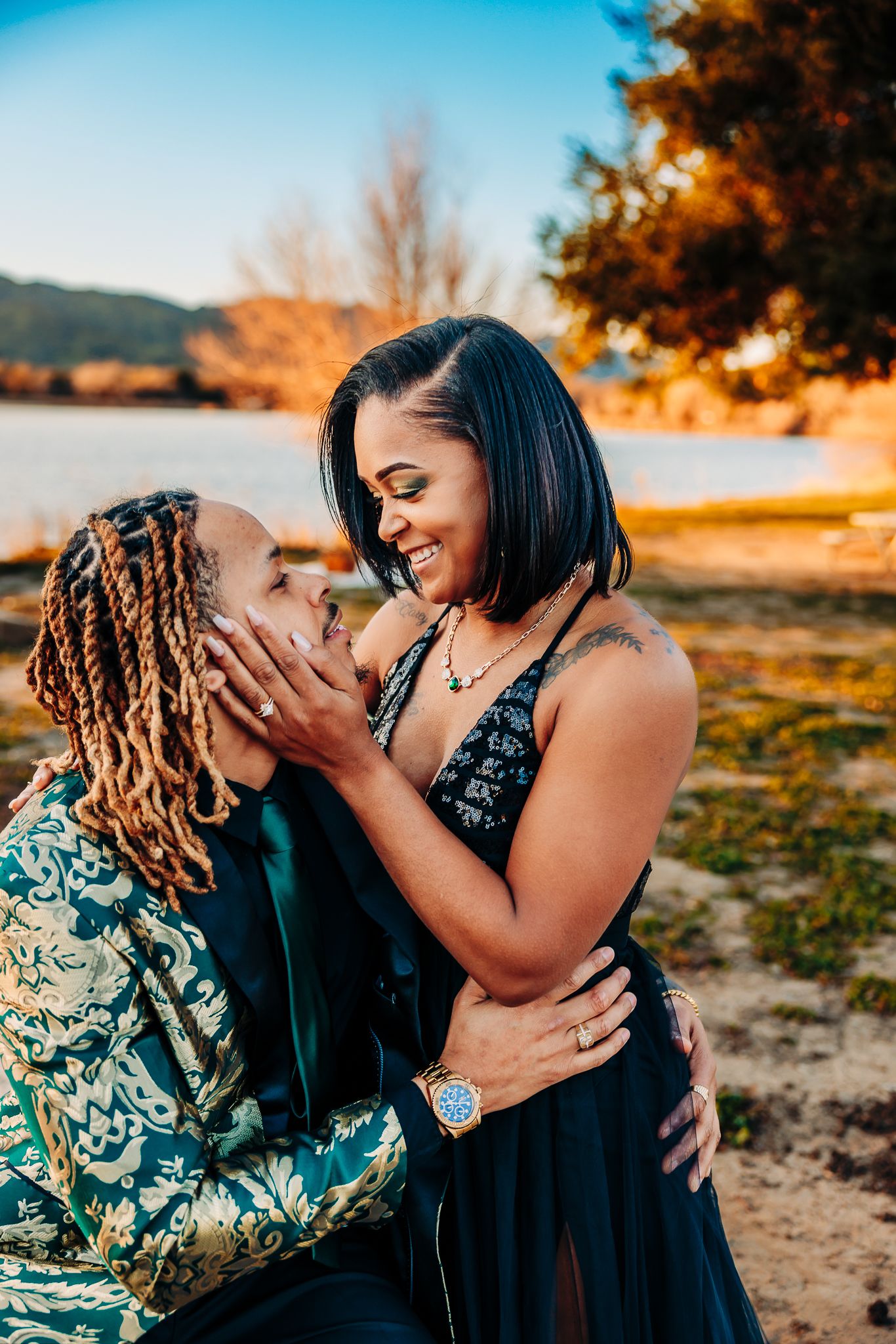 Romantic couple embraces against white wall with green ivy backdrop.