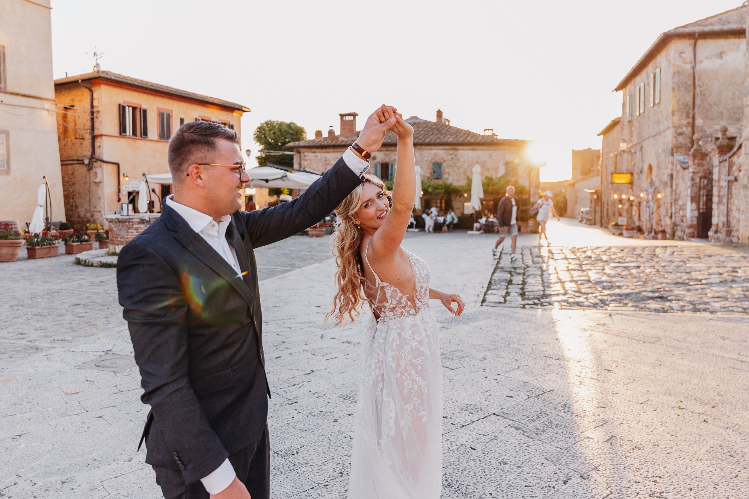 Ein fröhlicher Tanzmoment zwischen Jungvermählten auf einem sonnenverweckten italienischen Platz.