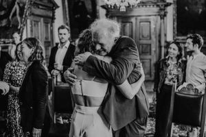 Emotionale Umarmung während eines Hochzeitsempfangs an einem kunstvollen Ort.