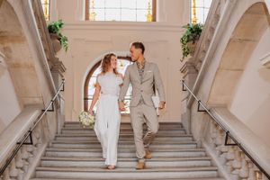 Hochzeitspaar geht elegante Marmortreppen in formeller Hochzeitskleidung hinunter.