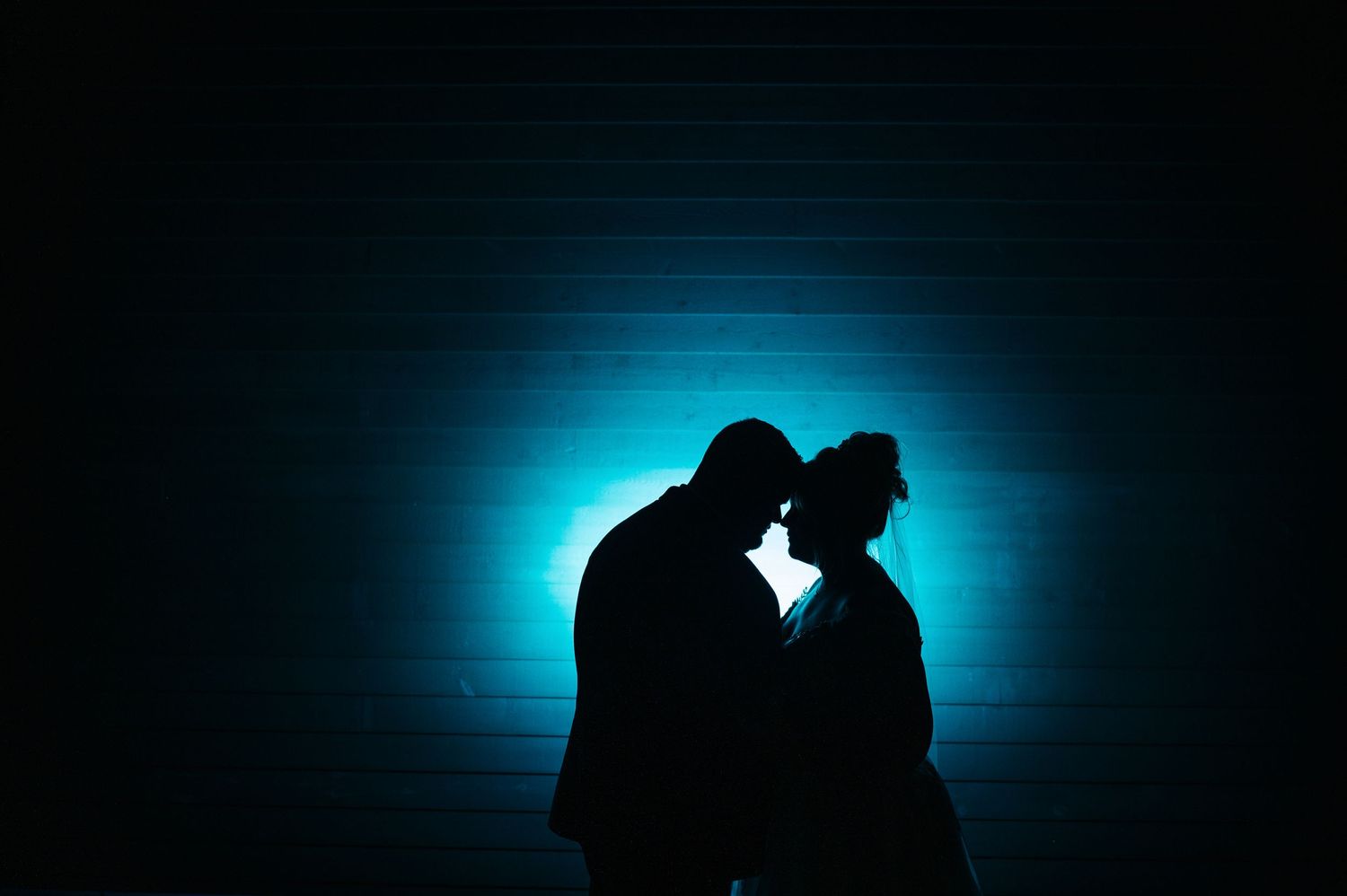 a silhouette of a couple forehead to forehead with a blue color.