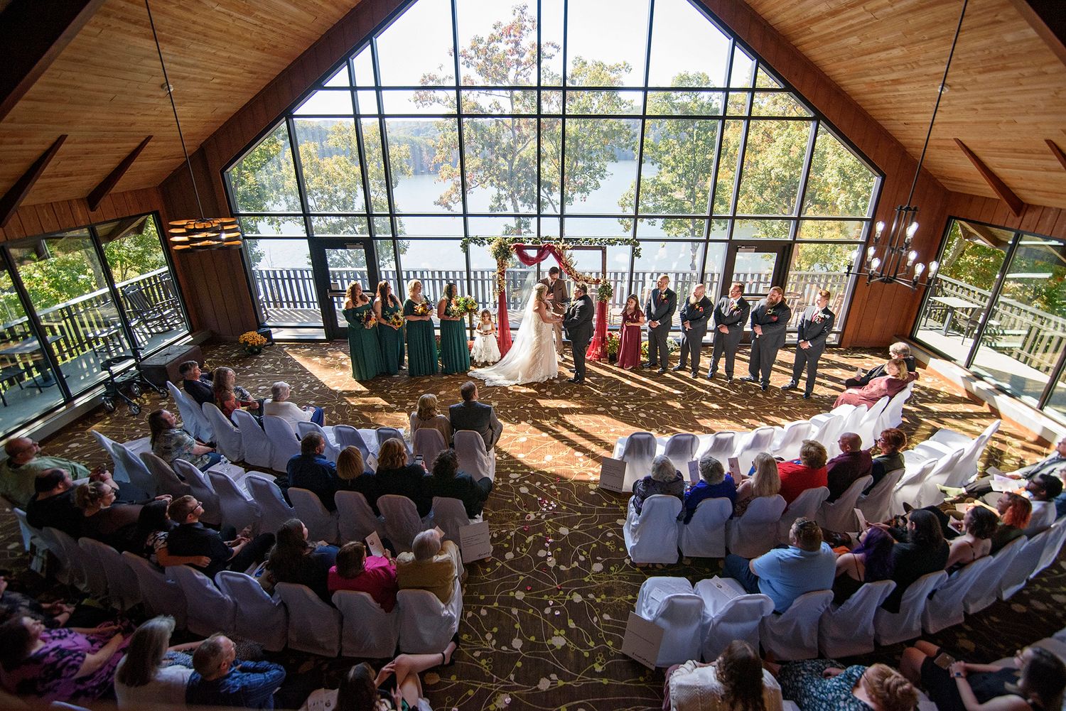 Guests gather in a rustic wooden chapel during an intimate wedding ceremony overlooking mountain scenery.