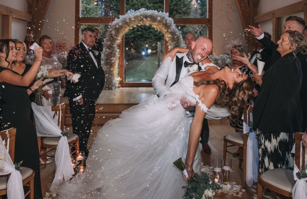 Wedding celebration with guests throwing confetti inside an elegant venue. Mill Barns Wedding