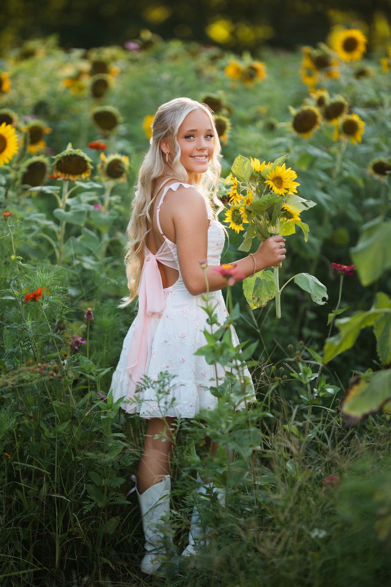 White dress portrait in sunflower field holding fresh picked flowers. Middle TN senior photographer.