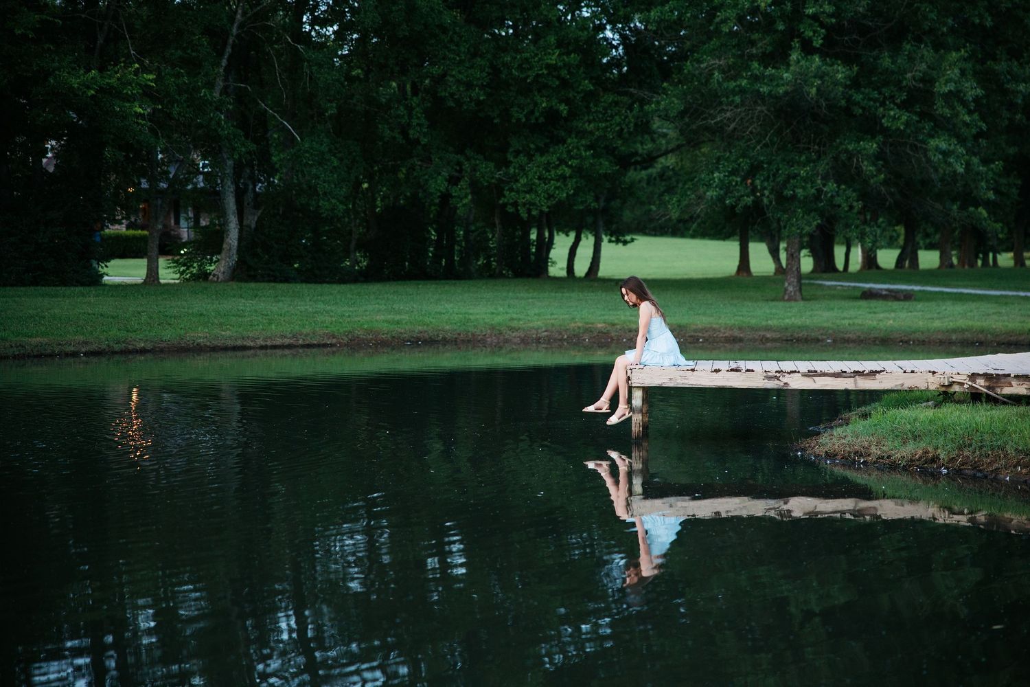 A romantic wedding photoshoot in a scenic park with a serene lake and lush greenery in the background.