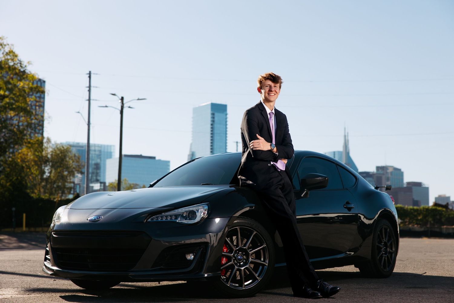 Luxury sports car photographed against Nashville downtown skyline with senior guy.  Middle TN senior photographer.