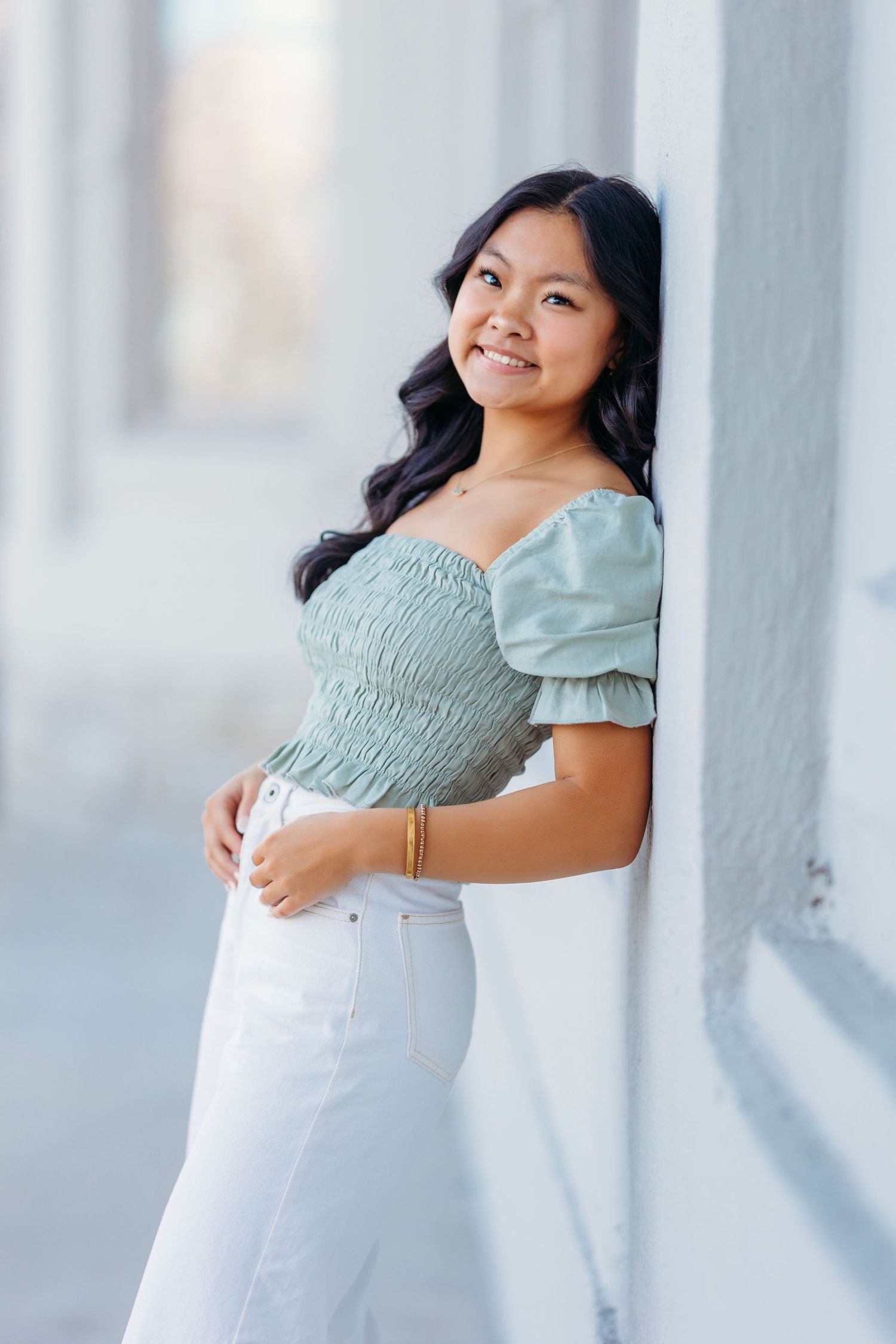 senior girl in mint green top and white pants posing against light wall. Middle TN Senior photographer