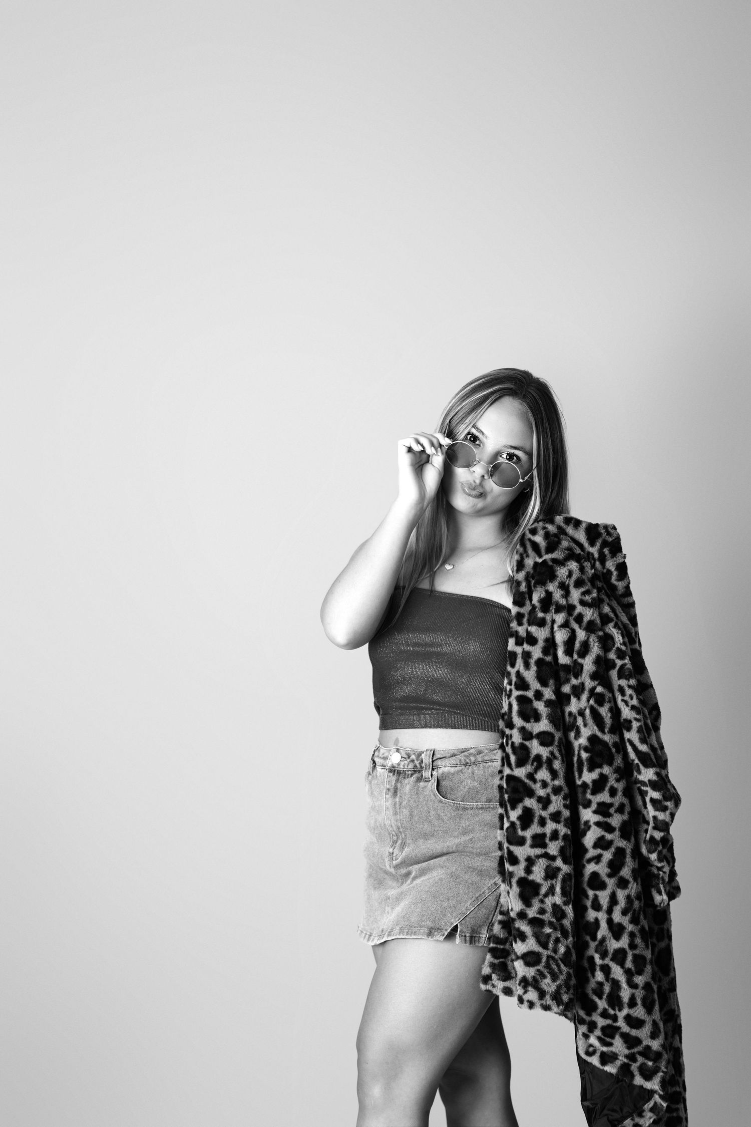 Fashion portrait with leopard print coat and denim shorts against grey background. Middle TN senior photographer.