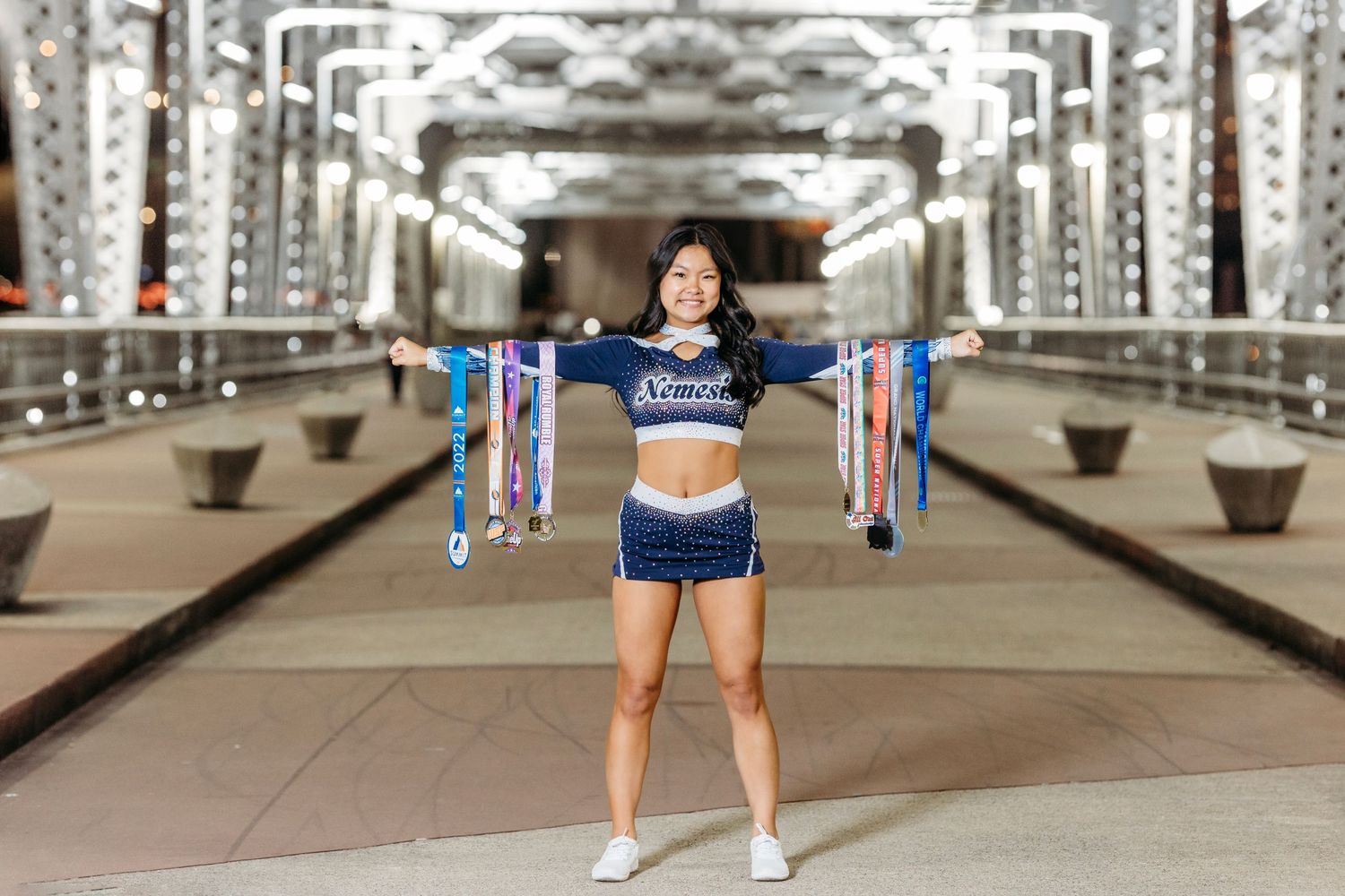 Athlete displaying medals on bridge with urban architecture in background. Middle TN Senior photographer