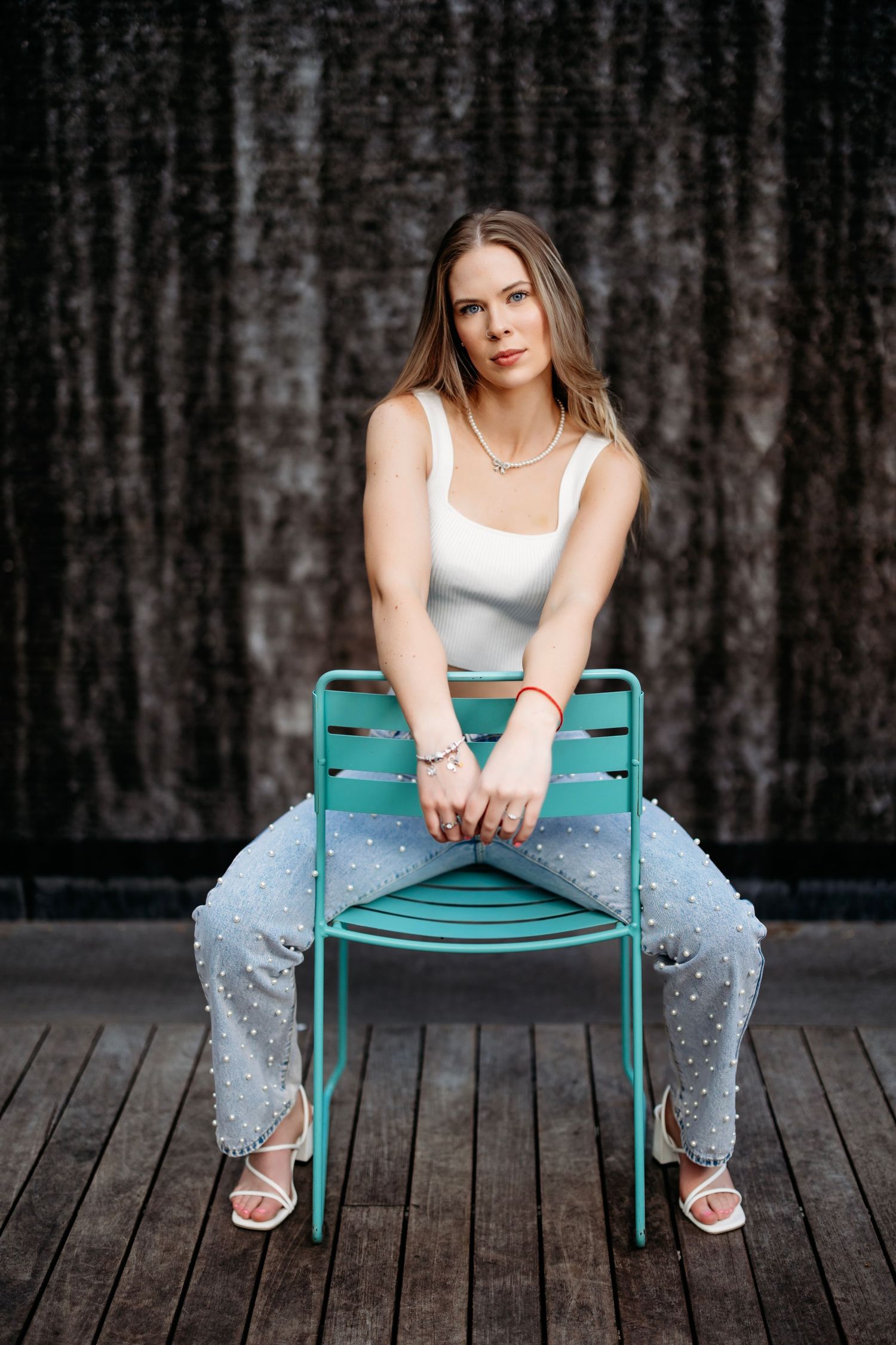 Artistic portrait session on wooden deck with turquoise chair creating modern composition. Middle TN Senior photographer