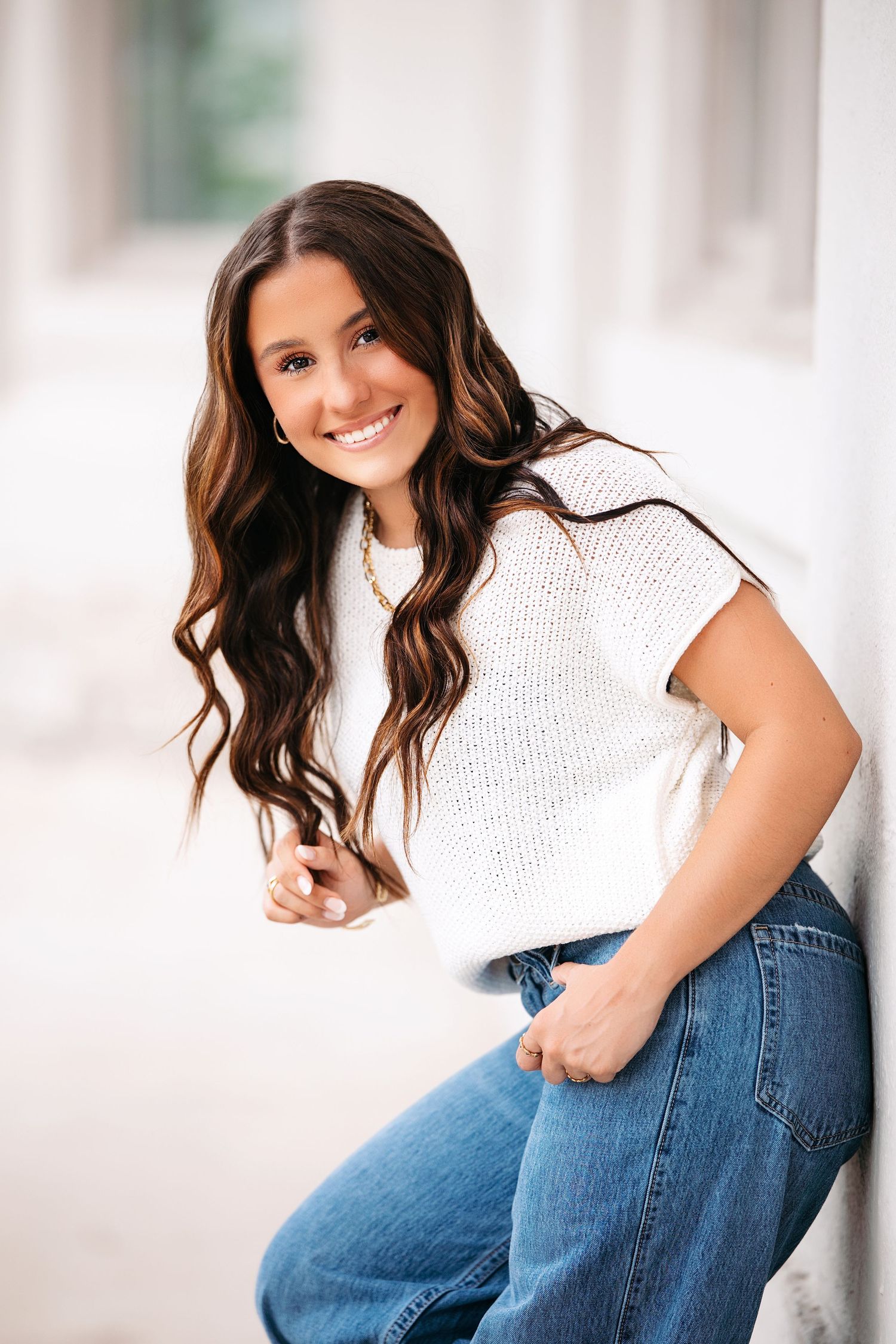 Portrait series of someone wearing a white sweater and jeans while sitting against a bright white background.