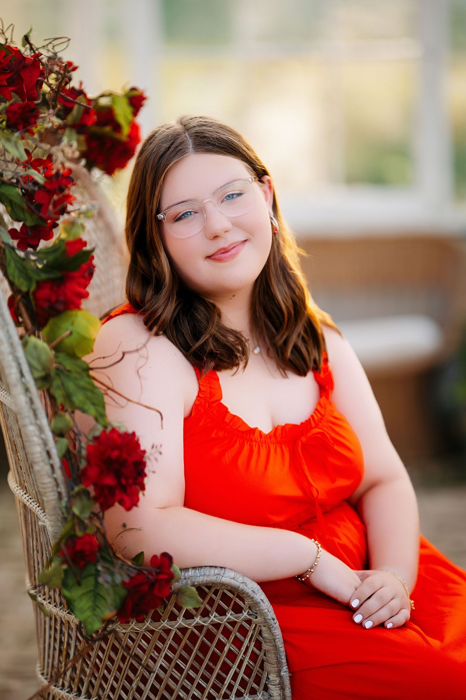 Portrait session in a wicker chair with red dress and floral decorations. Middle TN senior photographer.