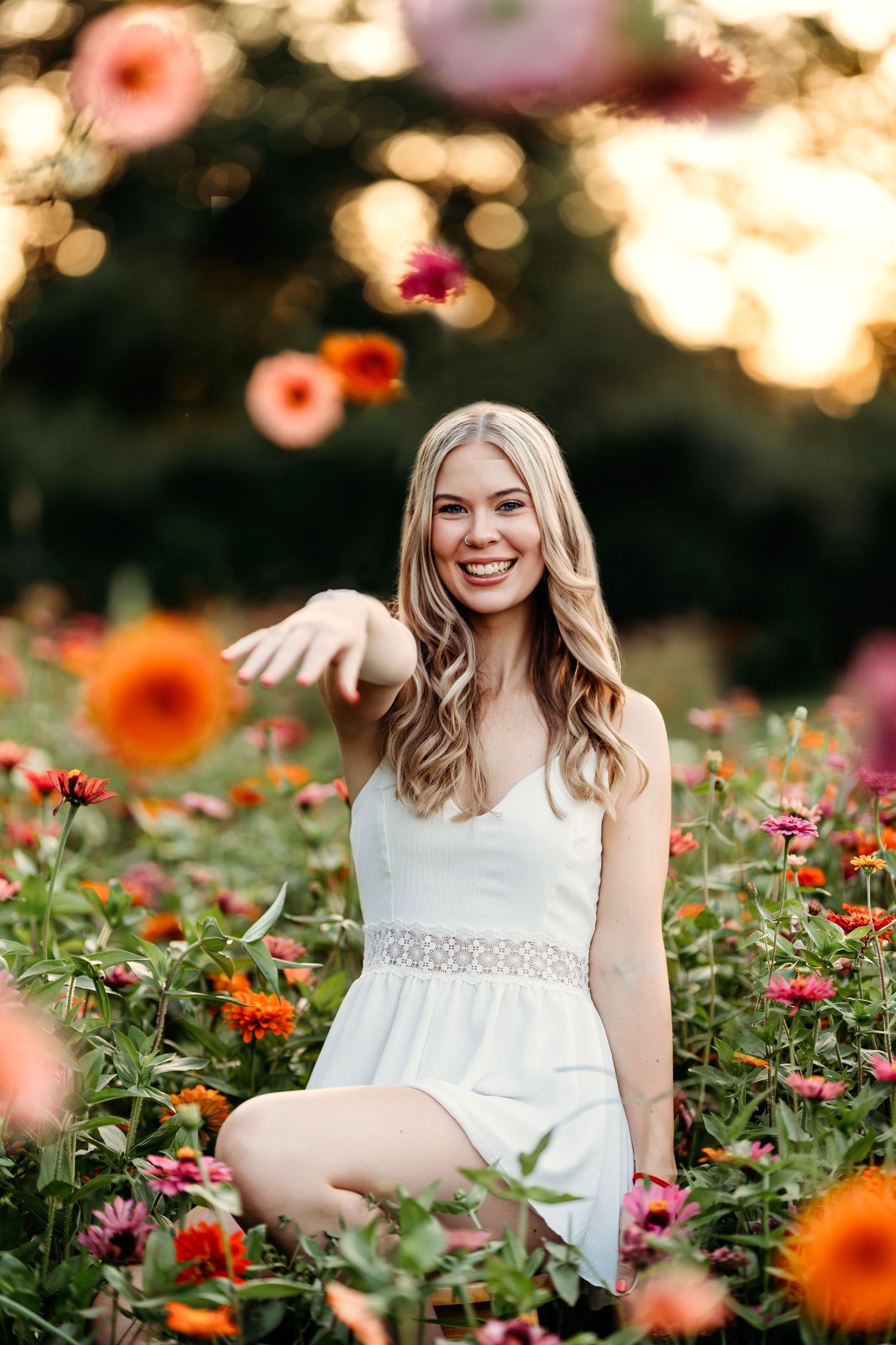 White summer dress contrasts beautifully with vibrant orange and pink wildflowers at sunset. Middle TN Senior photographer