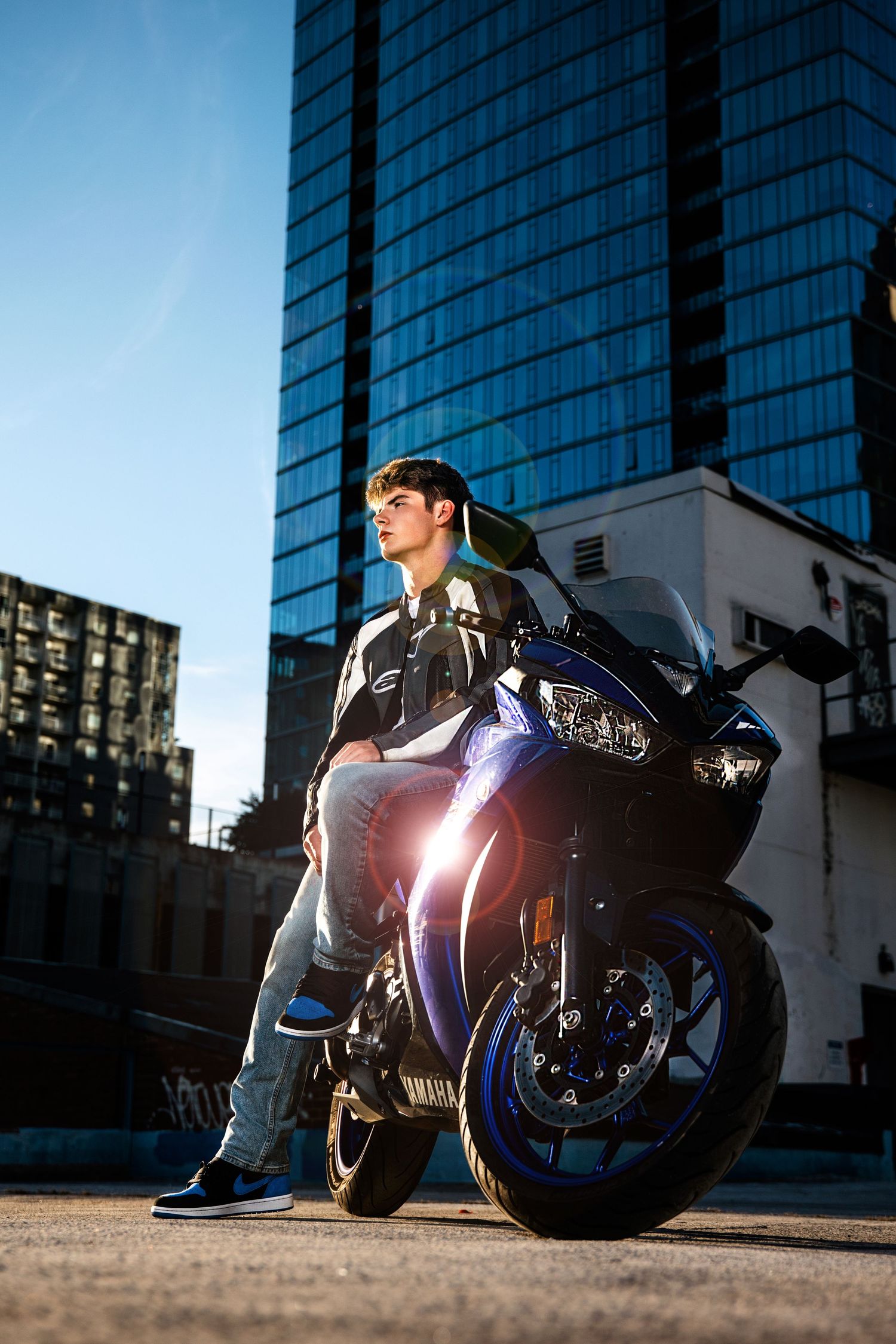 Senior guy on Sleek motorcycle parked in front of modern glass downtown Nashville building during sunset.  Middle TN senior photographer.