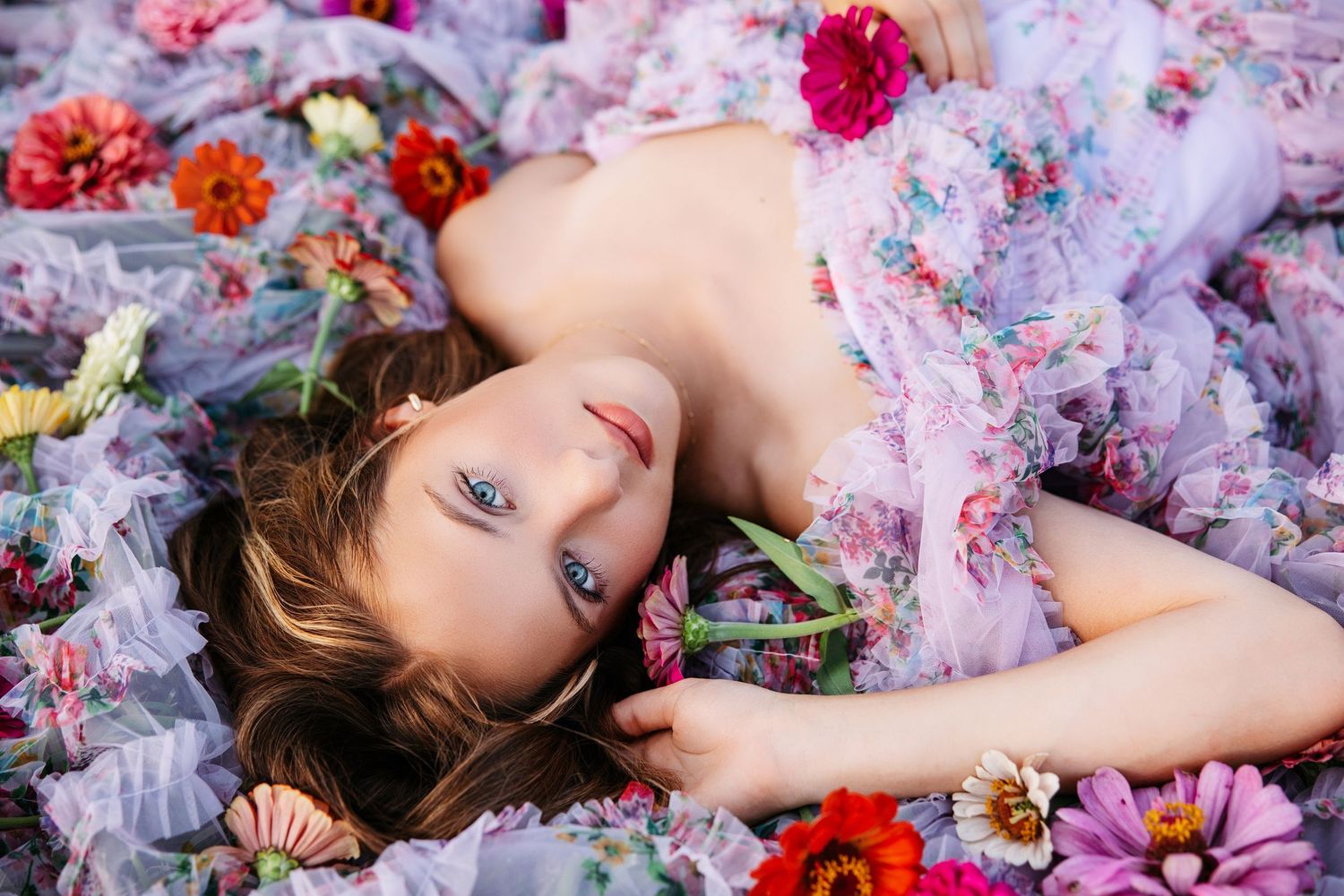 A dreamy artistic portrait surrounded by scattered pink and red flowers on a soft floral fabric background.