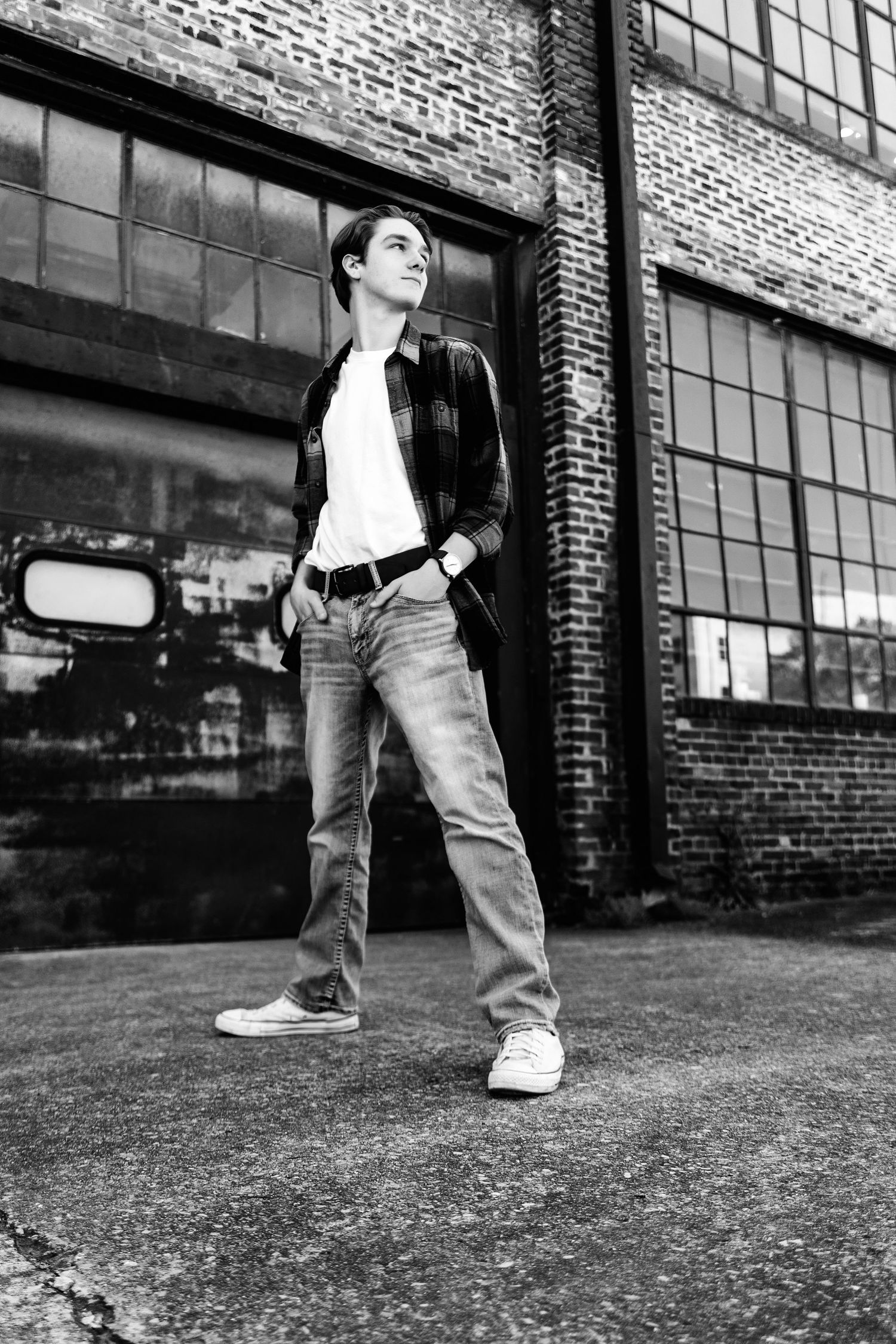 Black and white photo if senior near a brick industrial building in Nashville. Middle TN Senior photographer