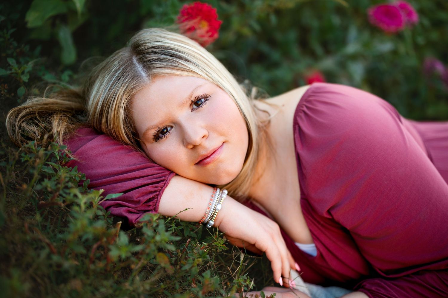 Artistic portrait session in a garden with vibrant red and pink roses. Middle TN senior photographer.