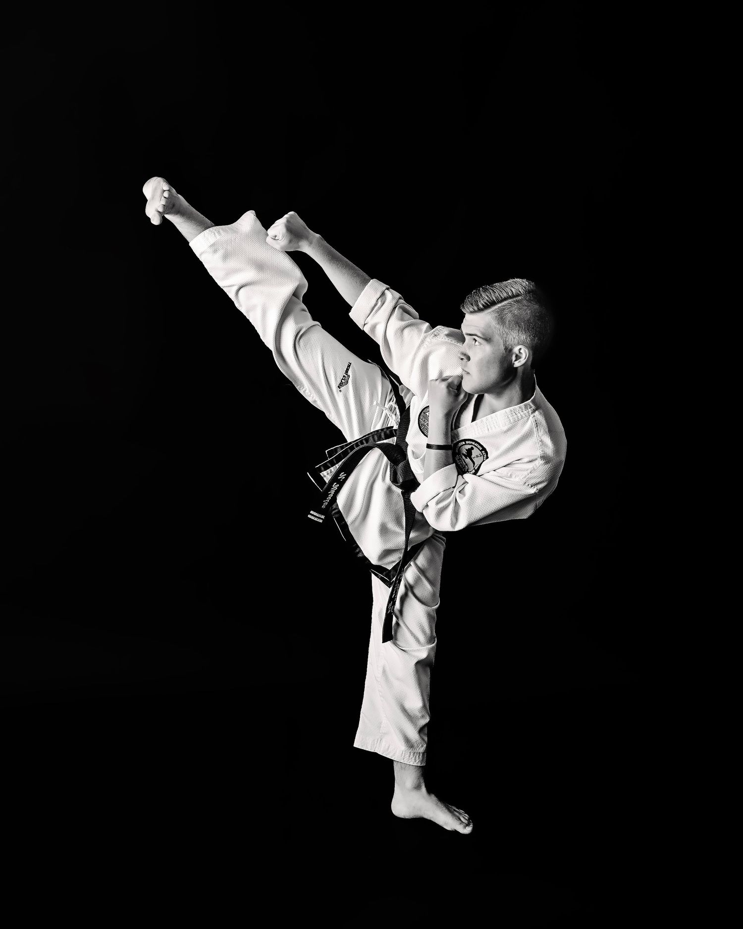 Series of martial arts high kicks demonstrated in black and white against dark background. Middle TN Senior photographer