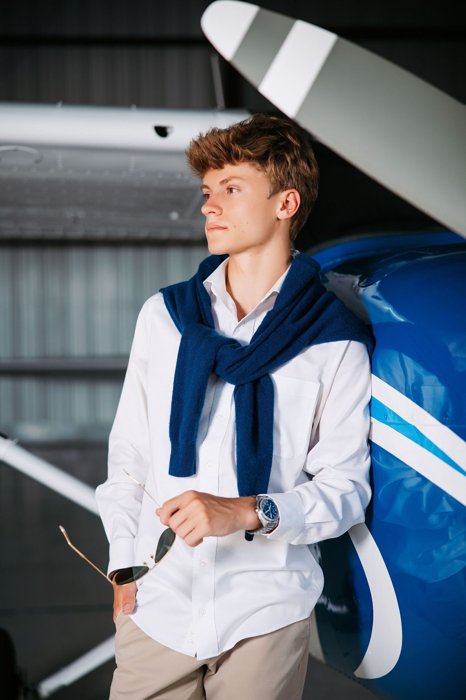 Aviation themed senior guy portrait series with white shirt and navy scarf against an aircraft. Middle TN senior photographer.