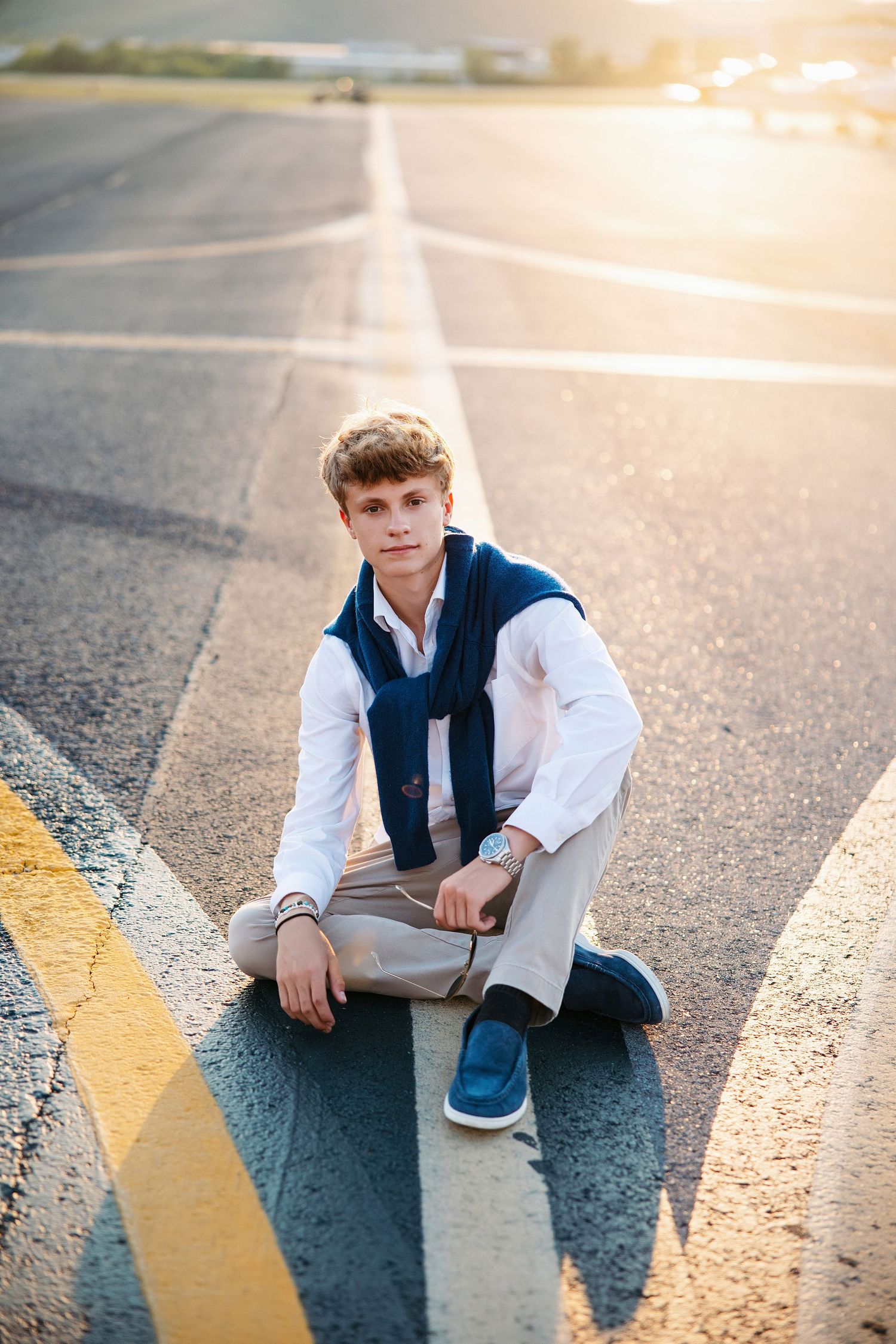 Senior guy sitting on yellow parking lot lines during golden hour.  Middle TN senior photographer.