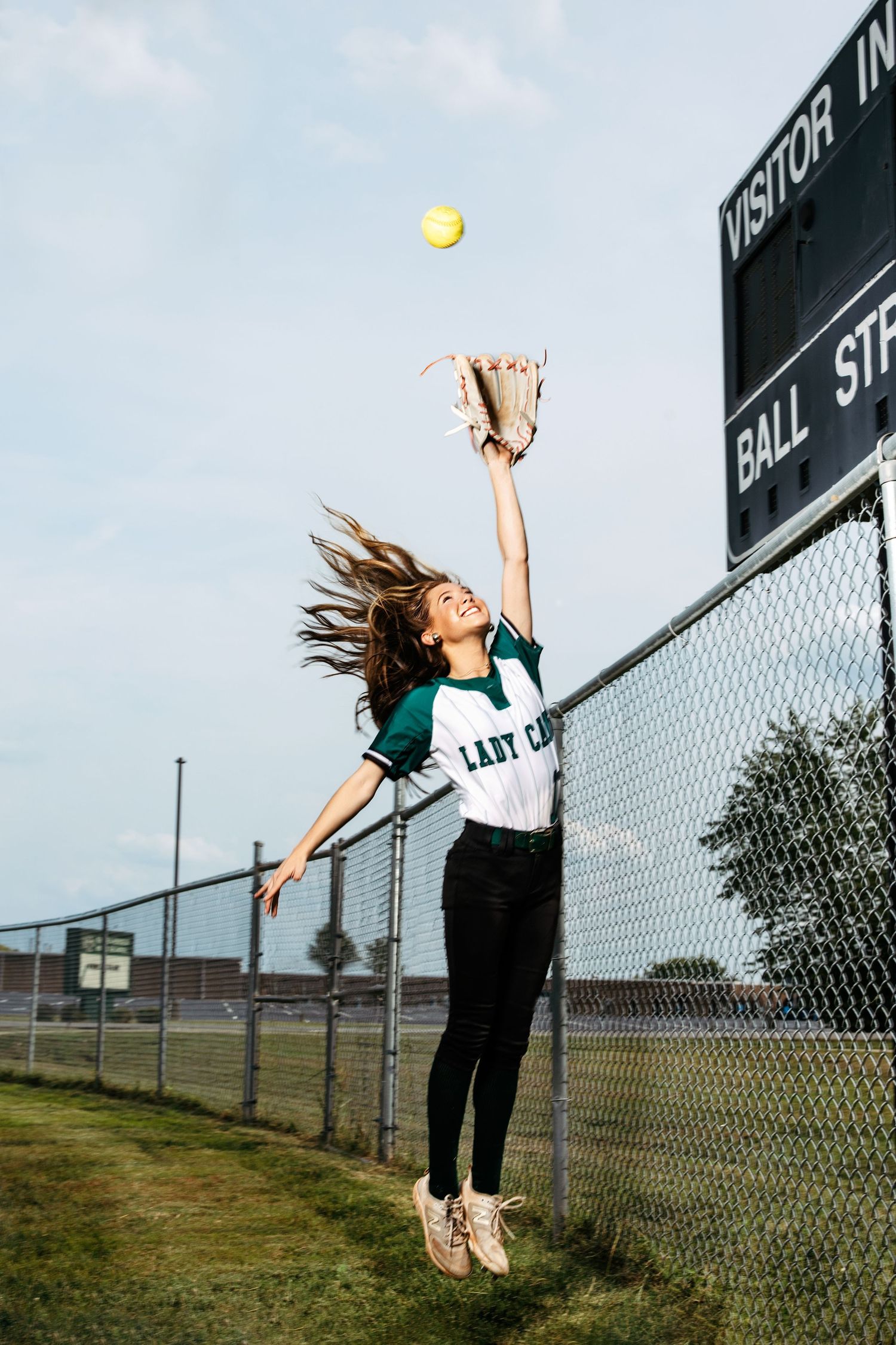 Volleyball player performing a sequence of serving motions against a chain-link fence on an outdoor court.