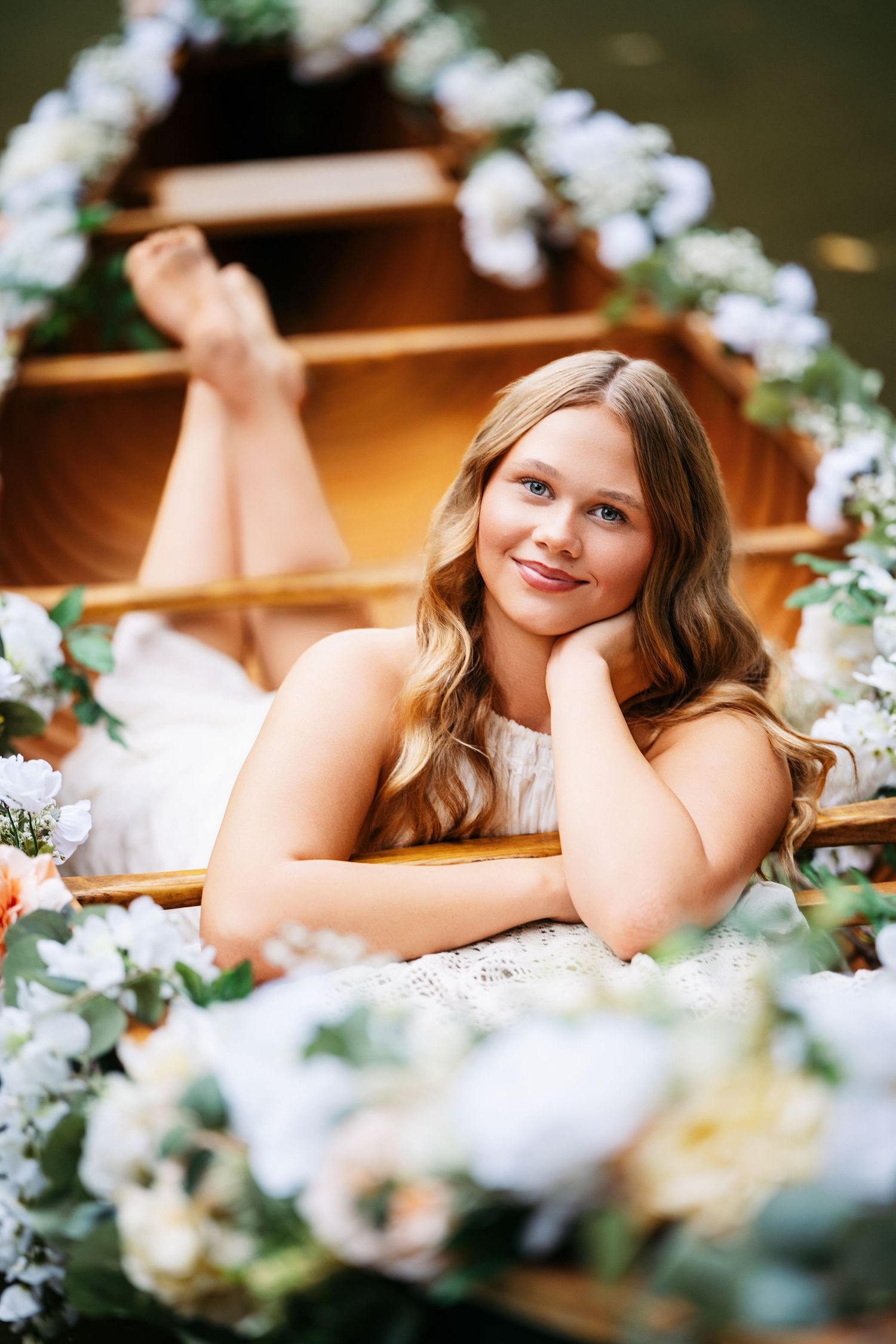 Romantic bridal boudoir photo session with soft floral decorations and warm lighting.