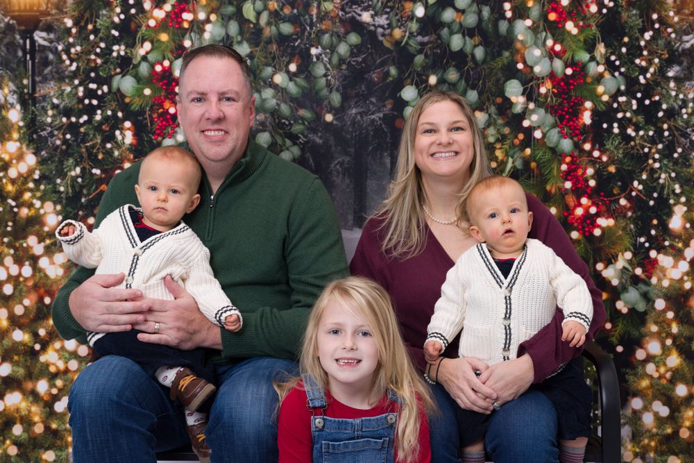 Studio family holiday portrait with festive backdrop showing parents and young children