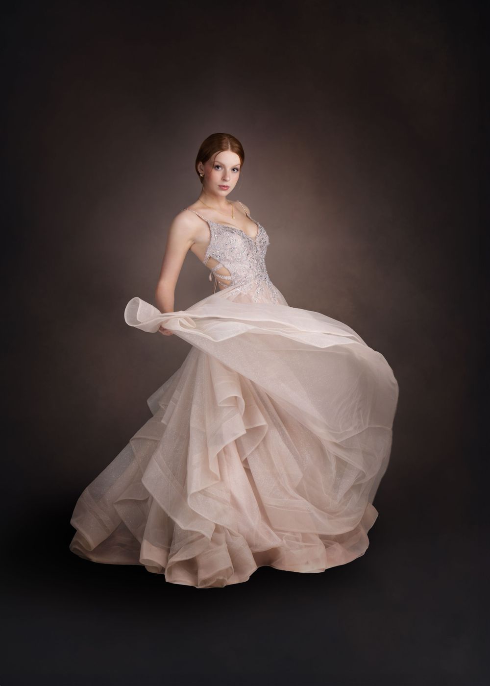 Fine art image of high school senior girl twirling a prom dress against a formal backdrop