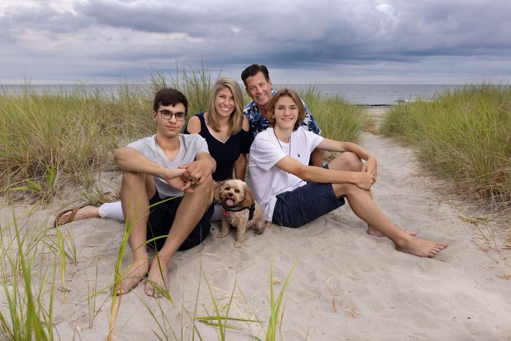 Family with pet sitting on beach for family photoshoot