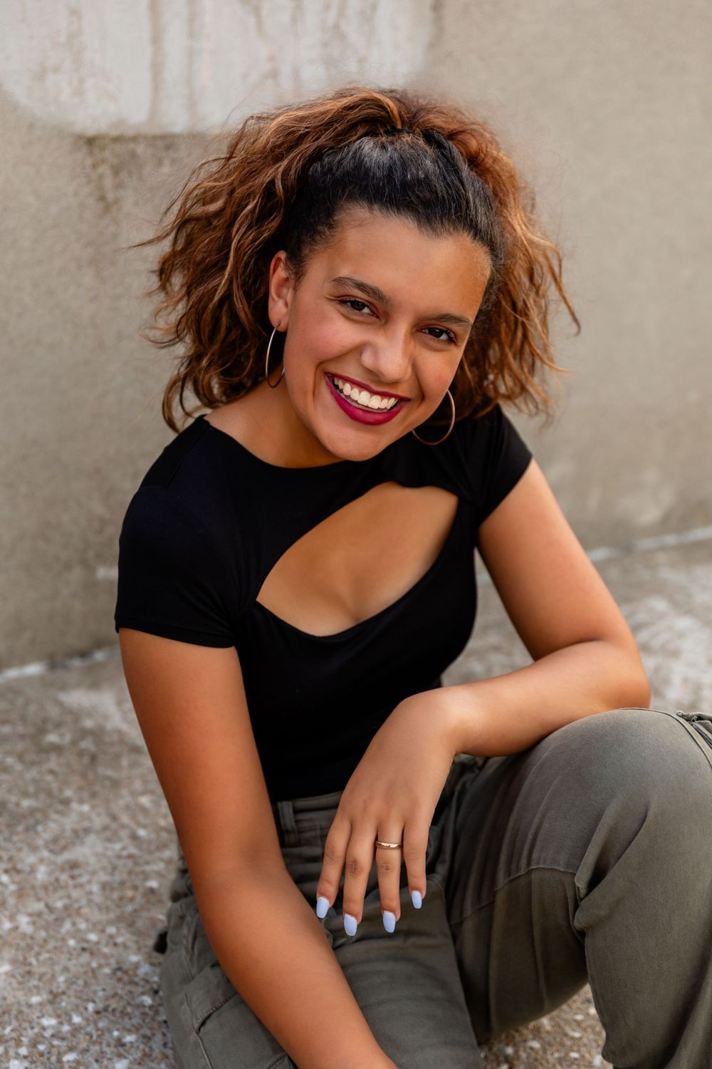 Casual portrait session against neutral wall wearing black top in Omaha, NE