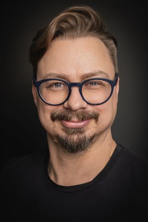 A series of portraits showing a person with glasses and facial hair making different playful expressions against a dark background.