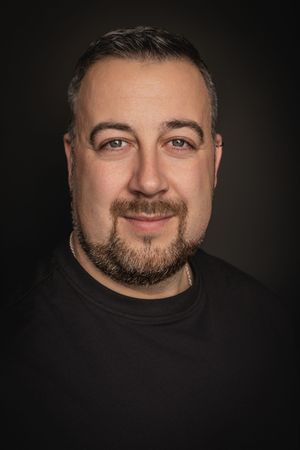 Professional headshot portraits against dark background showing facial expressions and beard in dramatic lighting.