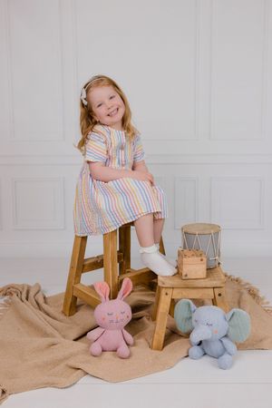 A series of playful photos with stuffed bunny toys and wooden stools against a white backdrop.
