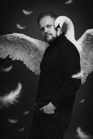 Artistic black and white photo series showing a person in dark clothing with ethereal white angel wings and falling feathers.