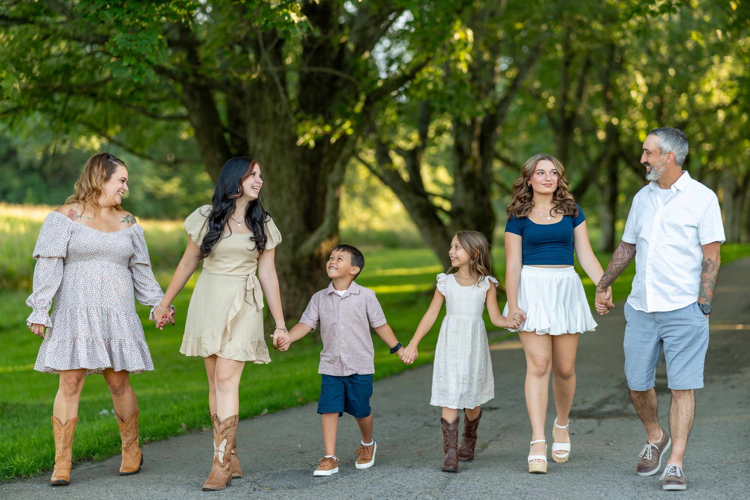 A group walking hand in hand down a tree-lined path wearing coordinated casual outfits.
