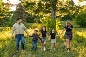 Family walking together through a sunlit meadow during golden hour in a series of connected photos.