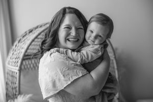 Black and white photo series showing tender moments between a parent and child in a wicker chair.