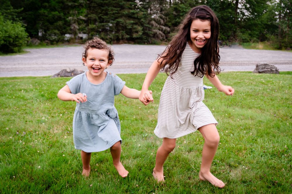 Children running and playing together on grass in a carefree summer scene.