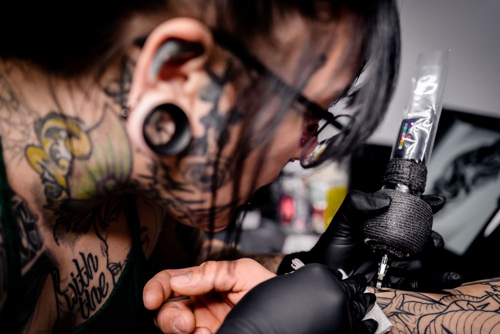 Close-up of a tattoo artist at work with machine and ink.