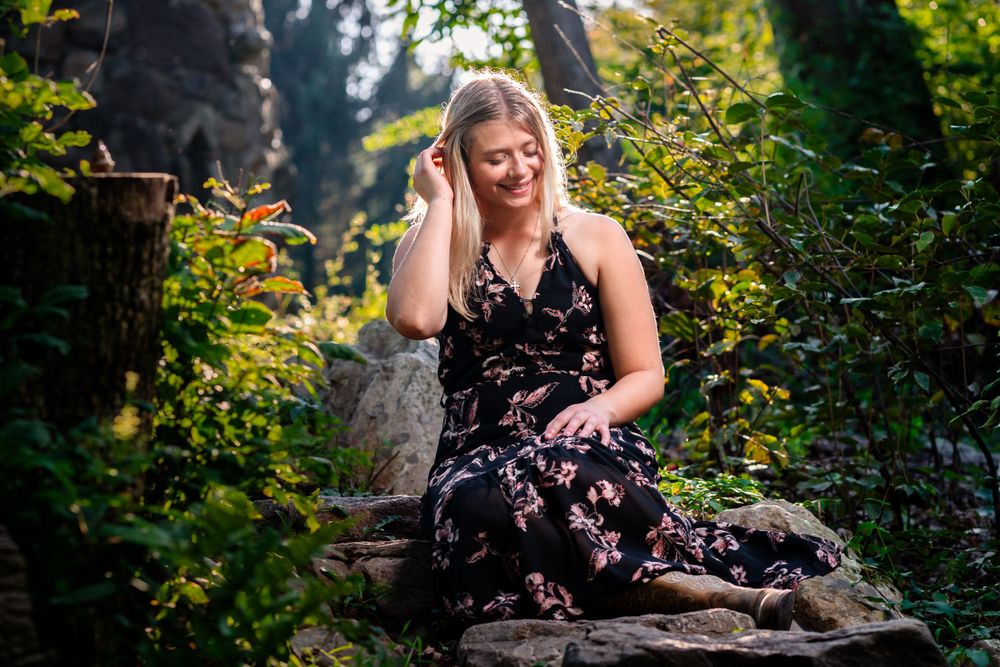A floral dress against lush garden foliage on a stone wall.