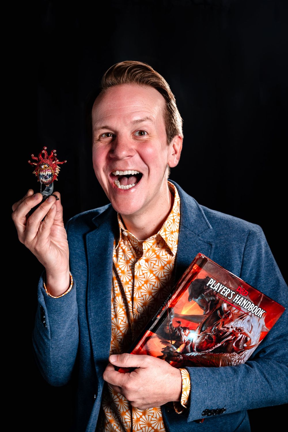 Person in blue blazer enthusiastically displays snack products against dark background.