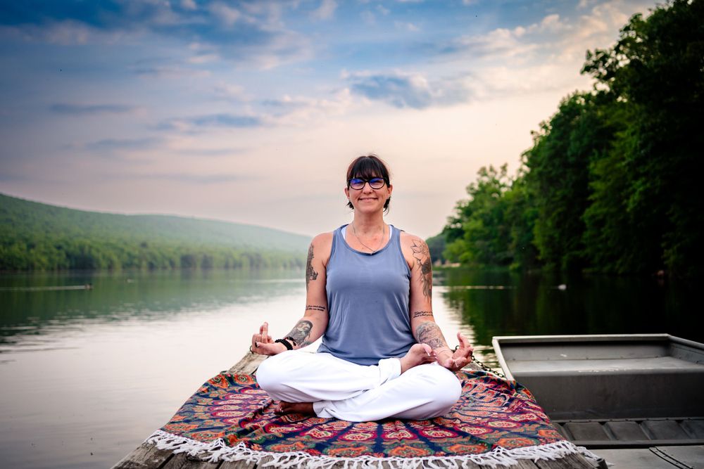 A peaceful meditation scene on a patterned blanket in a boat on a serene lake.