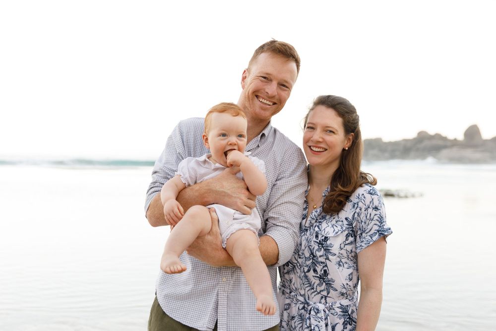 Happy family enjoys time together while standing on a sunny beach near the ocean.