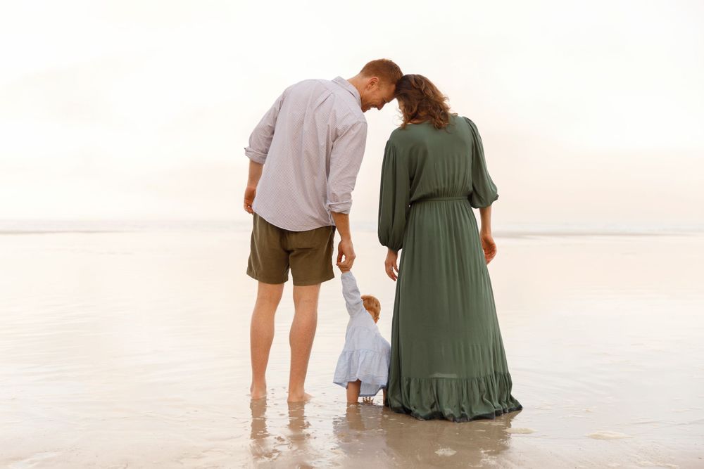 Family walking together on sandy beach during sunset in tranquil setting.