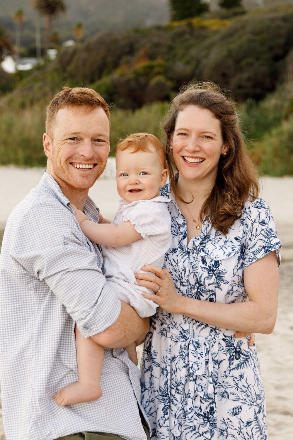 A joyful family portrait taken outdoors on a sunny day, with everyone smiling and embracing.