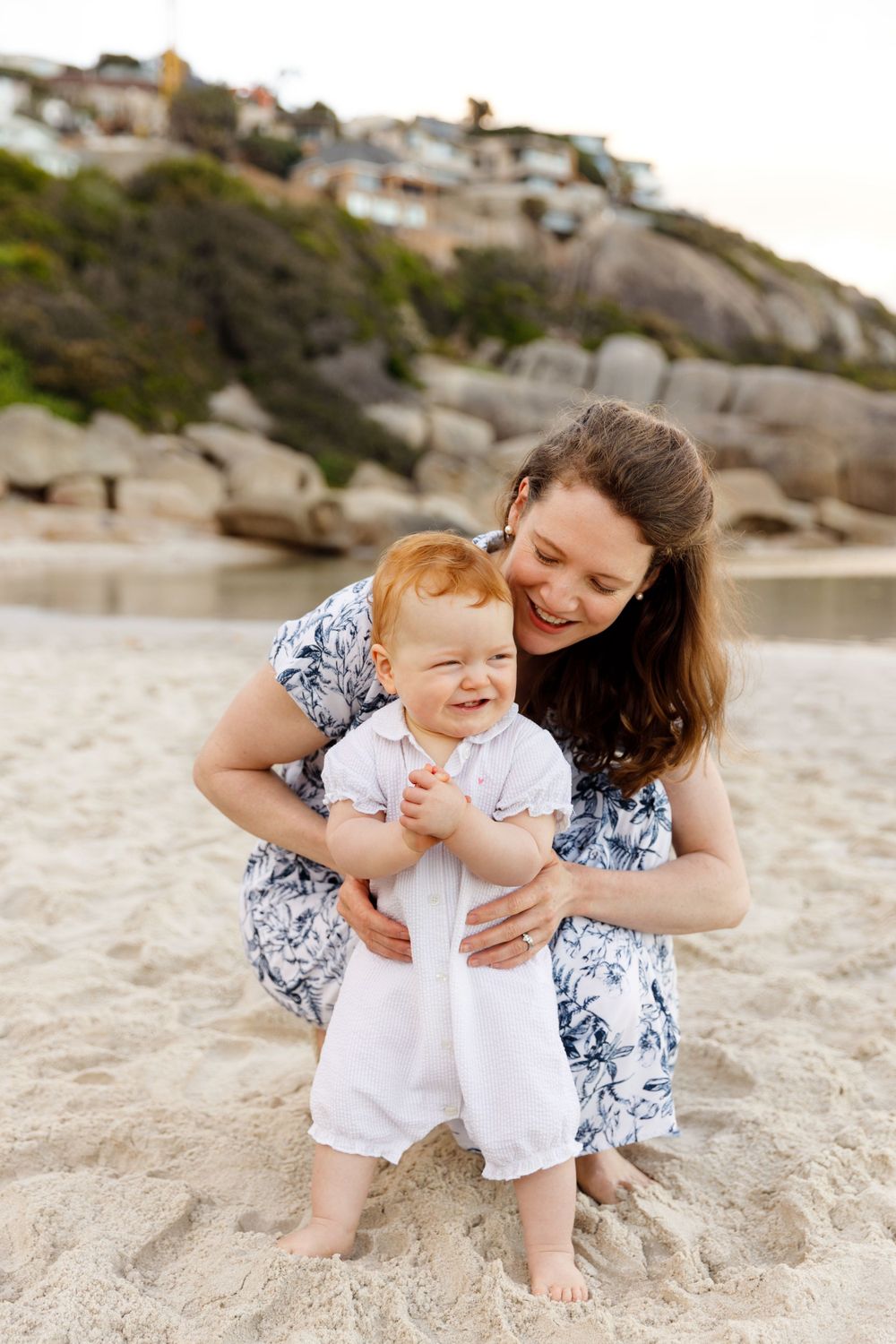 A heartwarming moment shared between two people in blue and white outfits sitting together on a sandy beach.