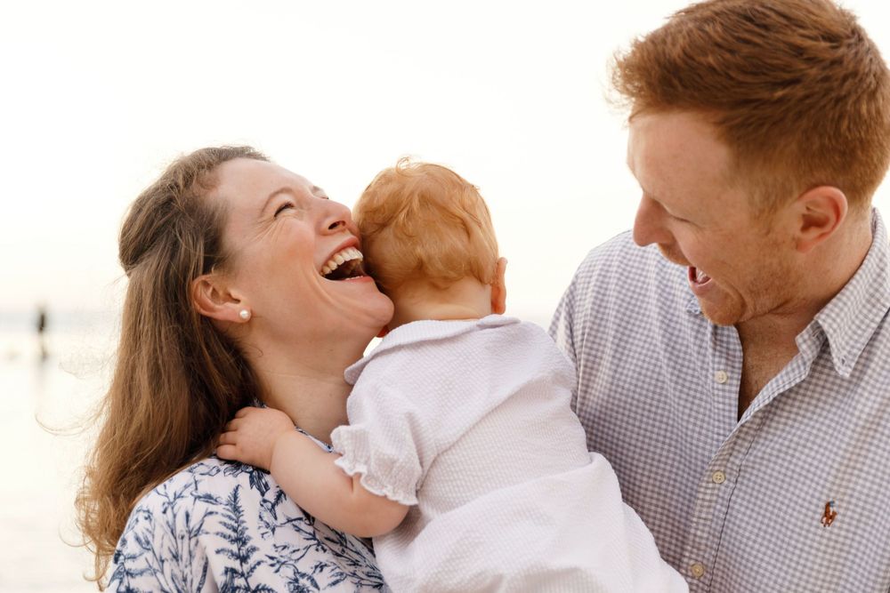 A family shares a joyful moment laughing together outdoors during a warm sunny day.
