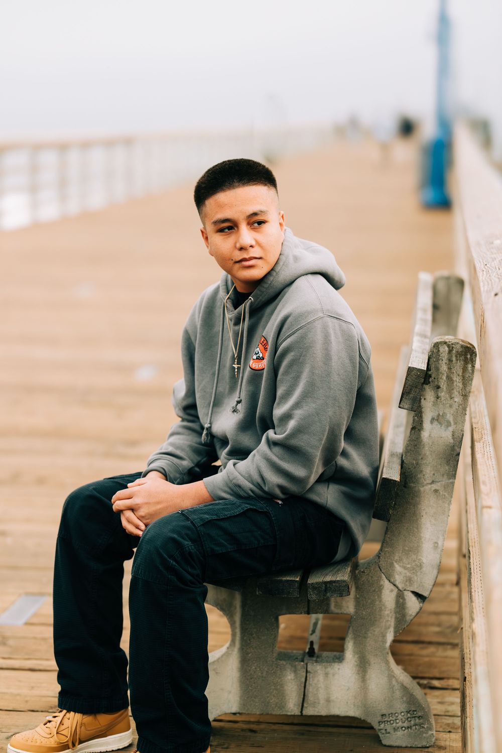 Senior boy sitting on a bench on the pier at Avila Beach, CA